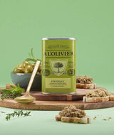 A L'Olivier Provençale Olivenöl auf grünem Hintergrund mit grünen Oliven, frischen Kräutern und Bruschetta – mediterran gewürztes natives Olivenöl extra für Antipasti, Gemüsegerichte, Pasta, Fisch und die provenzalische Küche