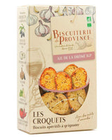 Produktbild der Biscuiterie de Provence „Les Croquets – Ail de la Drôme IGP“: Verpackung mit Knoblauch-Illustrationen und Sichtfenster, gefüllt mit knusprigen Aperitif-Brotscheiben mit Mandeln
