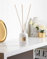 Collines de Provence Duftdiffuser Neroli mit weißen Duftstäbchen auf weißem Regal neben goldfarbenem Tablett, Vase mit Blumen und dekorativen Wohnaccessoires.