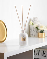 Collines de Provence Duftdiffuser Neroli mit weißen Duftstäbchen auf weißem Regal neben goldfarbenem Tablett, Vase mit Blumen und dekorativen Wohnaccessoires.