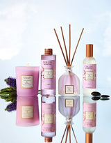 Collines de Provence Duftkollektion Patchouli & Tonkabohne mit Duftkerze, Duftdiffuser, Raumspray und Nachfüllung auf spiegelnder Oberfläche