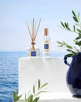 Duftkollektion „Sillage Marin“ von Collines de Provence mit Duftstäbchen-Diffusor und Raumspray vor einer mediterranen Küstenkulisse. Die Produkte sind auf einer weißen Terrasse mit Blick auf das Meer arrangiert und werden von Olivenzweigen sowie einer blauen Keramikvase ergänzt. Die frische Duftkomposition erinnert an eine belebende Meeresbrise und schafft eine entspannte, maritime Atmosphäre in Wohn- und Wellnessbereichen.