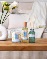 Collines de Provence Tiaré Duftkerze, Raumspray & Diffuser auf Holztisch neben Blumen Vase