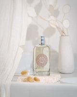 Durance Eau de Toilette Camélia Éclatant als elegante Lifestyleaufnahme mit Flakon auf Steinplatte, dekoriert mit Trockenblumen und hellem, minimalistischem Hintergrund