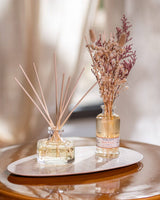 Durance Floral Reed Diffuser Ambre Précieux Duftdiffuser mit Trockenblumen und Duftstäbchen auf Tablett im Wohnraum