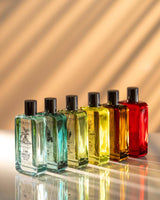 Durance Eau de Toilette Homme Duftkollektion mit mehreren farbigen Flaschen in Reihe auf reflektierender Oberfläche