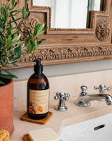 Durance Flüssigseife Mandarine & Granatapfel im Badezimmer am Waschbecken neben Wasserhahn und Pflanze