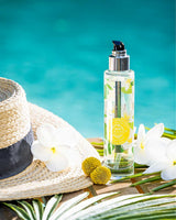 Durance Körperöl Sensual Monoi 100ml in transparenter Flasche am Pool mit Blumen und Strohhut in sommerlicher Szene