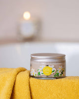 Durance Körperpeeling Sensual Monoi im Glas auf gelbem Handtuch im Badezimmer, pflegendes Body Scrub mit exotischem Monoi-Duft