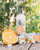 Durance Bodylotion und Seife „Orange Blossom“ im Freien mit frischer Orange und weißen Blüten auf Holztisch