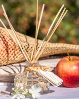 Durance Raumduft Diffuser Apfelblüte 100ml dekoriert mit Apfel und weißen Blüten in natürlichem Frühlingsambiente im Freien