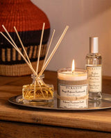 Stimmungsvolle Wohnszene mit Durance Duftset Silberzeder bestehend aus Diffuser, Duftkerze und Raumspray auf einem Holztisch bei warmem Kerzenlicht