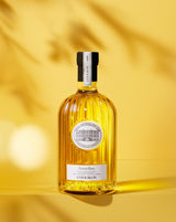 Château d'Estoublon Olivenöl Bouteillan 500ml in geriffelter Glasflasche, frontal vor warmem gelbem Hintergrund mit Schatten