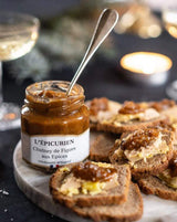 Geöffnetes Glas L'Épicurien Feigen-Chutney mit Gewürzen als Brotaufstrich auf Baguettes mit Pastete.