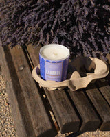 Panier des Sens Duftkerze Lavendel aus der Provence in dekorativem Kerzenglas auf rustikaler Holzbank mit getrocknetem Lavendel in stimmungsvoller Outdoor-Dekoration