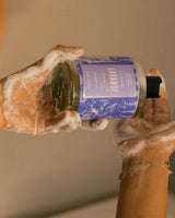 Panier des Sens Duschgel Lavendel 500ml bei der Anwendung. Das Lavendel-Duschgel in transparenter Flasche wird in den Händen gehalten und erzeugt Schaum.