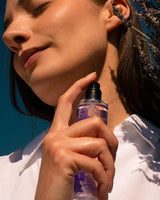 Panier des Sens Eau de Toilette Lavendel aus der Provence 50ml bei der Anwendung am Hals mit Lavendelzweigen in natürlicher provenzalischer Atmosphäre unter blauem Himmel