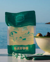 Panier des Sens Refill Flüssigseife Duft Olive auf Tisch mit Oliven und Meer im Hintergrund