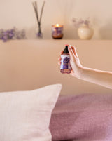 Zartrosa Glasflasche mit Raumspray von durance, das in einem Raum von einer weiblichen Hand versprüht wird