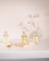 Trio Refill-Flaschen von Durance nebeneinander arrangiert als Lifestyle-Bild vor einer Blume