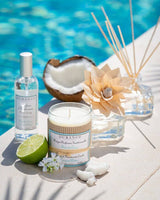 Raumspray, Duftkerze, Holzduftblume und Diffuser mit Rattanstäbchen von Durance neben einer Limette am Pool arrangiert