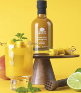 A L'Olivier Mango-Essig, 200ml Flasche dekoriert mit Mango, Limette und fruchtigen Zutaten als Serviervorschlag für sommerliche Salate und Dressings