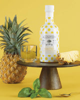 A L'Olivier Vinaigrette Ananas & Basilikum mit frischer Ananas, Basilikumblättern und Glas auf gelbem Hintergrund