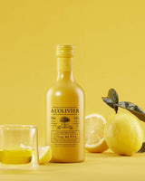A L'Olivier Zitronen-Maceration mit frischen Zitronen und Glas auf gelbem Hintergrund