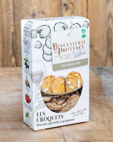 Produktbild der Biscuiterie de Provence „Les Croquets – Picodon AOP“: Verpackung mit Ziegenkäse-Illustrationen und Sichtfenster, arrangiert auf einem Holztisch mit sichtbaren knusprigen Aperitif-Brotscheiben