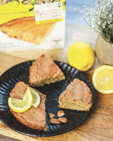 Biscuiterie de Provence Bio-Mandelkuchen mit Zitronengeschmack auf schwarzem Teller angerichtet, dekoriert mit Zitronenscheiben und Mandeln