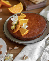 Biscuiterie de Provence Bio Orangenkuchen stilvoll auf einem Teller serviert und mit frischen Orangen dekoriert
