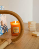 Collines de Provence Duftkerze Mandarine & Yuzu als dekorativer Blickfang auf einem Sideboard für eine fruchtig-frische und einladende Wohnatmosphäre.
