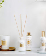 Collines de Provence Duftkollektion mit Duftdiffuser Neroli, Duftdiffuser-Nachfüllung Neroli, Raumspray Baumwolle und Duftkerze Baumwolle auf weißem Regal vor hellem Hintergrund.