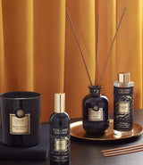 Collines de Provence Duftkollektion mit Duftkerze Schwarze Rose, Raumspray Ebenholz, Duftdiffuser Ebenholz und Duftdiffuser-Nachfüllung Ebenholz auf goldenem Tablett vor goldfarbenem Vorhang.