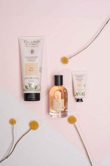 Collines de Provence Pflegeserie Weißer Tee mit Duschgel, Eau de Toilette und Handcreme, dekorativ arrangiert mit gelben Blüten.