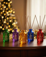Collines de Provence Raumduft Diffuser der Weihnachtskollektion in verschiedenen Farben vor festlich beleuchtetem Weihnachtsbaum