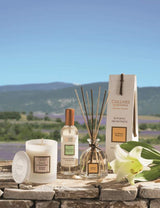 Collines de Provence Duftkerze, Raumspray und Duftdiffuser mit weißer Lilie auf einer Steinmauer vor einer Lavendellandschaft