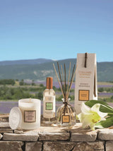 Collines de Provence Duftkerze, Raumspray und Duftdiffuser mit weißer Lilie auf einer Steinmauer vor einer Lavendellandschaft