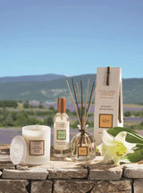 ollines de Provence Duftkerze, Raumspray und Duftdiffuser mit weißer Lilie auf einer Steinmauer vor einer Lavendellandschaft