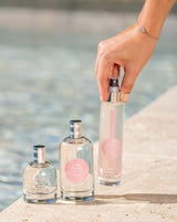 Durance Duftset Delicate Water Lily mit Körperspray und Parfumflaschen am Pool, Hand greift nach Flakon