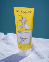 Durance Herren Shampoo & Duschgel Citron Corse in gelber Tube auf hellem Handtuch vor blauem Hintergrund