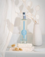 Durance Eau Fraîche Baumwoll-Moschus 100 ml als Sprayflakon in schlankem Design, präsentiert in heller, natürlicher Umgebung mit Steinpodest und Trockenblumen 