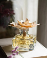 Durance Holzduftblume Edelamber mit dekorativer Holzblüte und elegantem Glasflakon auf rustikalem Holztisch mit stilvoller Wohnraumdekoration und Trockenblumen im Hintergrund