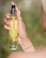 Durance Körperspray Sparkling Verbena in transparenter Flasche wird in der Hand gehalten, Anwendung im Freien