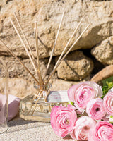 Durance Raumduft Diffuser Sanfte Pfingstrose 100ml dekoriert mit rosa Blüten in stilvollem Outdoor-Ambiente auf Natursteinfläche