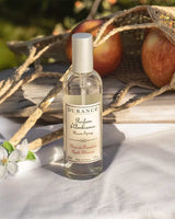 Durance Raumspray Apple Blossom im Außen-Setting mit Äpfeln, Stoff und Blüte im Sonnenlicht