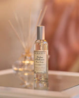 Durance Raumspray Cashmere auf Tisch vor Duftstäbchen in warmer, gemütlicher Wohnatmosphäre