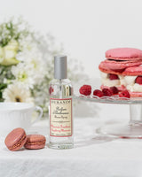 Durance Raumspray Raspberry Macaroon neben Macarons und Himbeeren auf gedecktem Tisch im hellen Ambiente