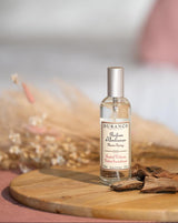 Durance Raumspray samtiges Sandelholz auf Holzbrett mit Sandelholz und dekorativen Trockenblumen in warmer Atmosphäre