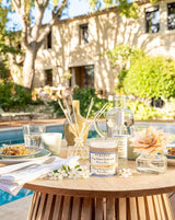 Sommerliches Stillleben mit Durance Kerze, Diffuser und Erfrischungen auf einer Terrasse mit Pool im Hintergrund